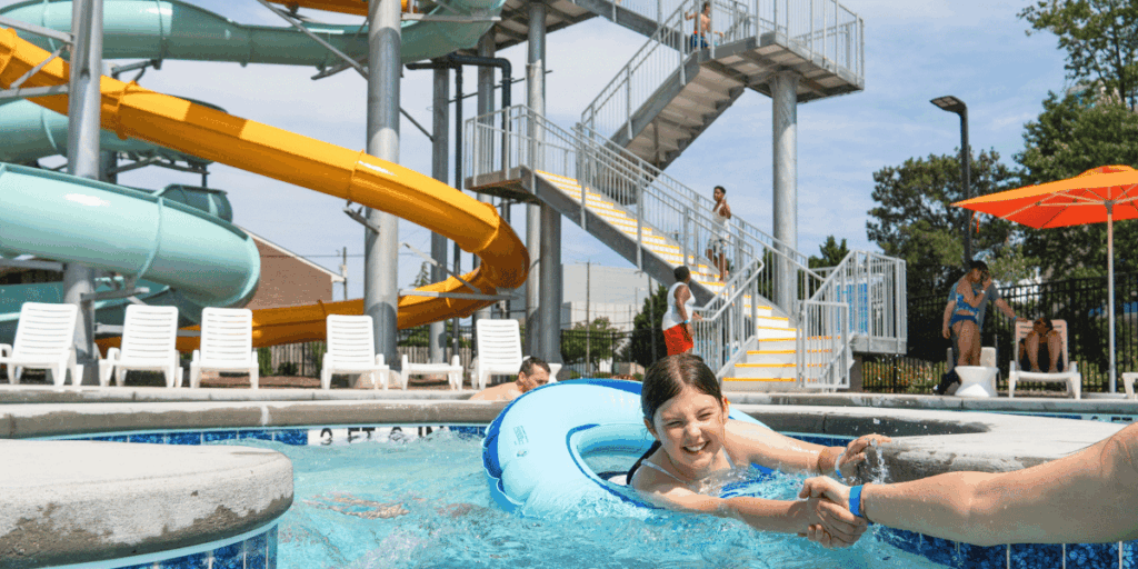 girl on floatie tube in lazy river with waterslide in background
