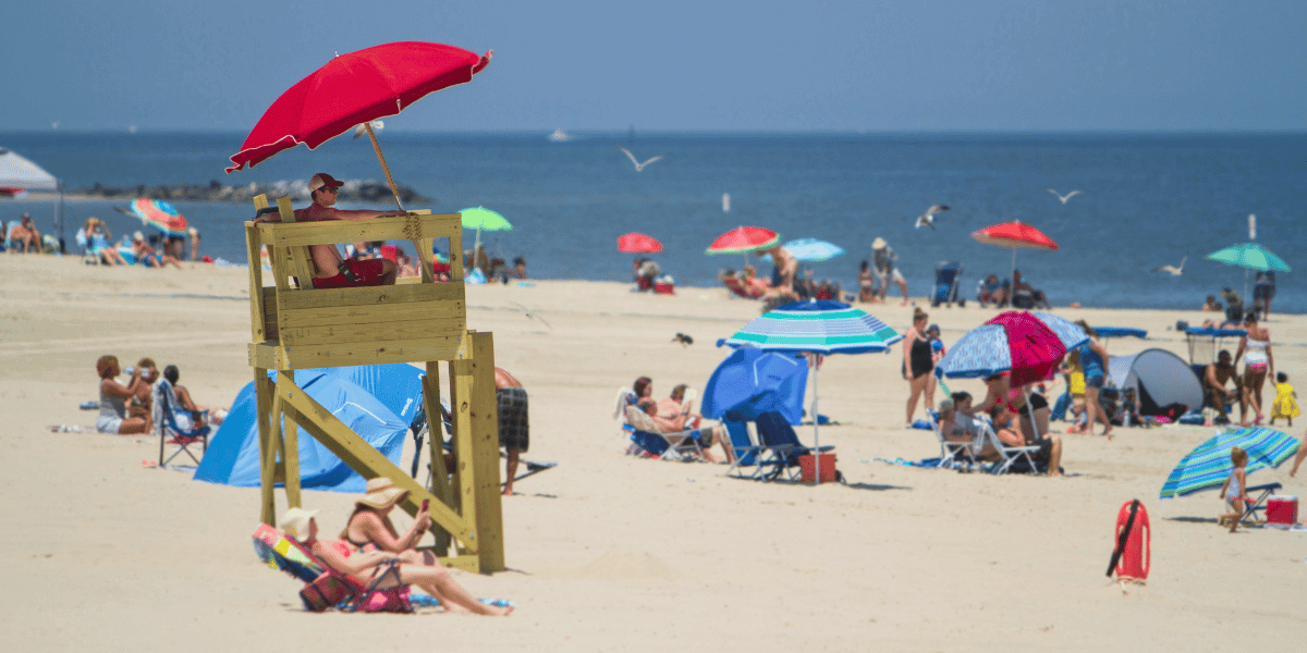 Lifeguard and vacationing families with colorful umbrellas at Buckroe Beach in Hampton, Virginia