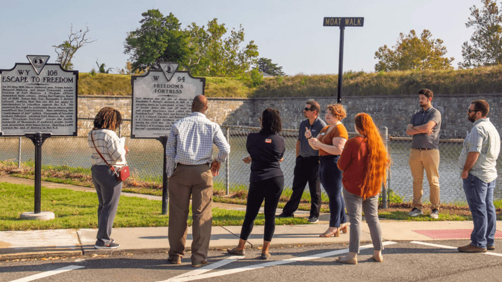 A group people touring fort monroe looking a the Freedom Fortress historical marker.