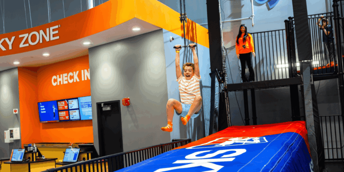 A child joyfully rides down indoor zipline as Sky Zone staff supervises. Link goes to indoor attraction blog post.