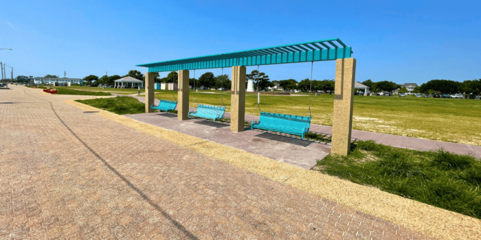 Blue adult-sized swinging benches on the paved walkway at Buckroe Beach in Hampton, Virginia
