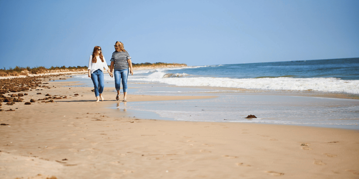 Two women walk along sandy beach shore at Grandview Nature Preserve in Hampton
